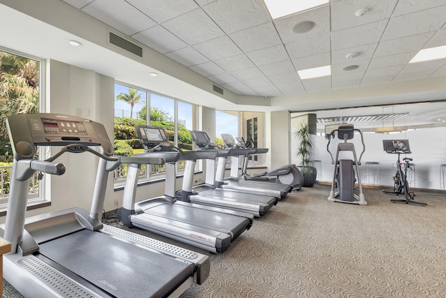 exercise room with a healthy amount of sunlight, visible vents, and a drop ceiling