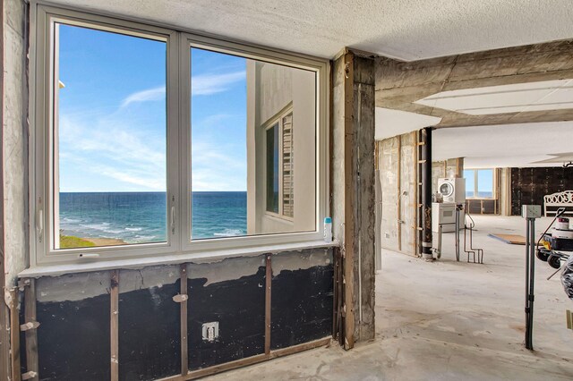 interior space featuring washer / dryer, a water view, and a textured ceiling