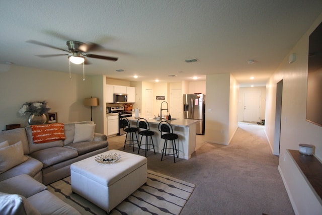 carpeted living room featuring sink, a textured ceiling, and ceiling fan