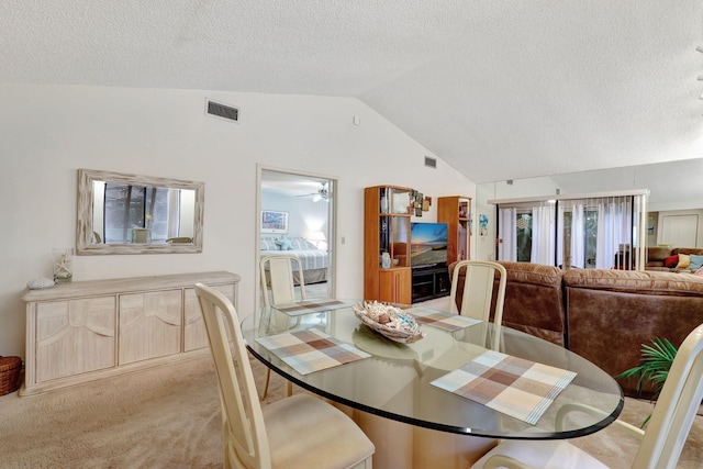 dining area with visible vents, light colored carpet, a textured ceiling, and vaulted ceiling