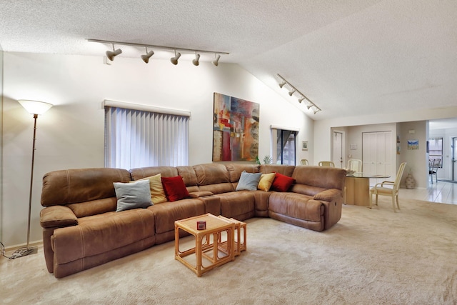 living room with lofted ceiling, a textured ceiling, light carpet, and track lighting