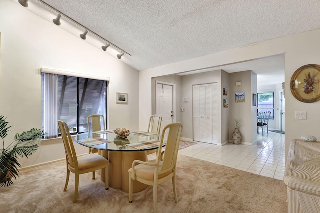 dining area with light carpet, a textured ceiling, light tile patterned flooring, baseboards, and vaulted ceiling