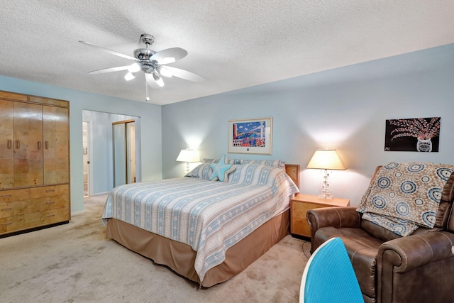 bedroom featuring ceiling fan, light colored carpet, a closet, and a textured ceiling