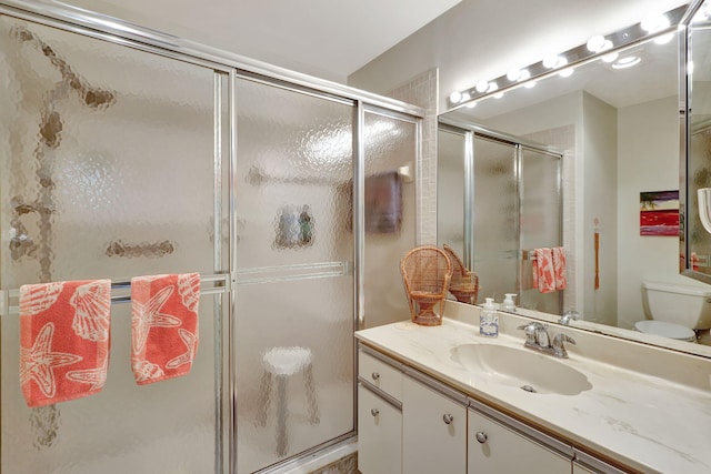 bathroom with toilet, a stall shower, and vanity