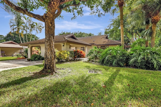 view of front of house with stucco siding, a tiled roof, concrete driveway, and a front lawn