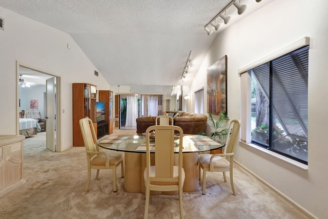 carpeted dining space featuring visible vents, lofted ceiling, a textured ceiling, and rail lighting