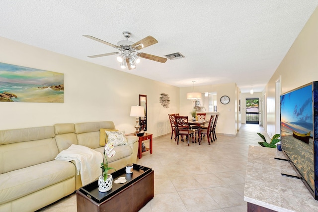 living room with light tile patterned flooring, a textured ceiling, and ceiling fan