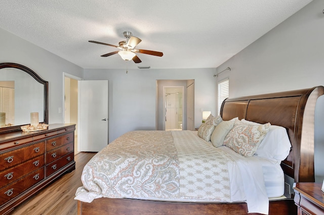 bedroom with hardwood / wood-style flooring, ceiling fan, a textured ceiling, and connected bathroom