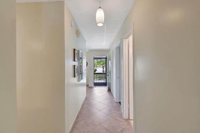 corridor featuring a textured ceiling and light tile patterned floors