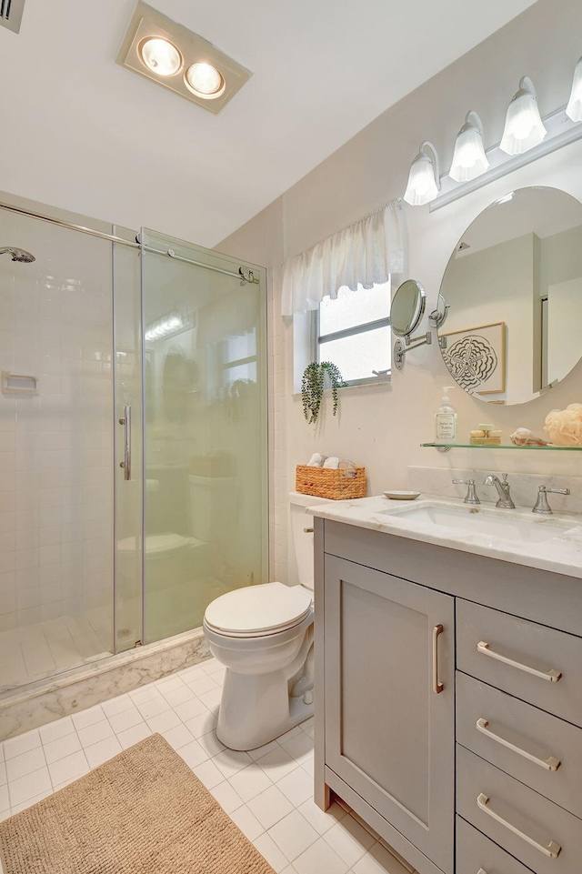 bathroom with tile patterned flooring, vanity, toilet, and a shower with door