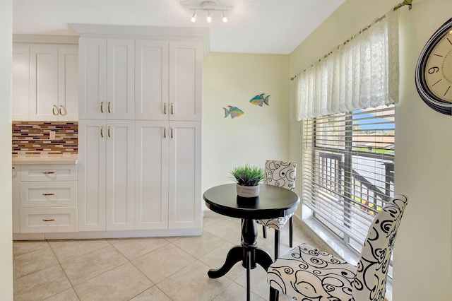 interior space featuring white cabinets, light tile patterned floors, and tasteful backsplash