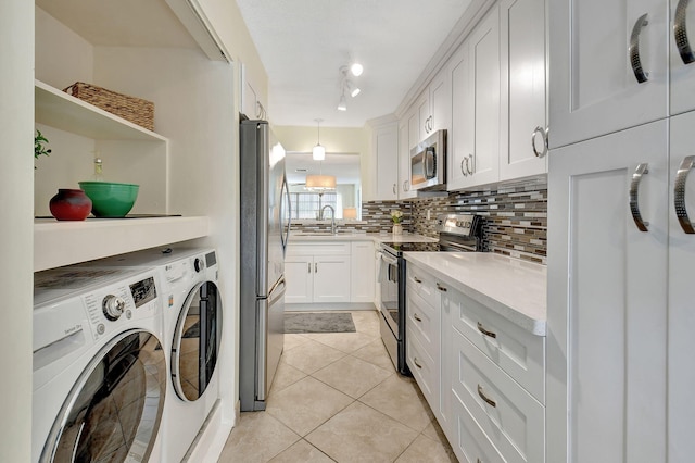 interior space with light tile patterned floors, white cabinetry, appliances with stainless steel finishes, decorative light fixtures, and independent washer and dryer