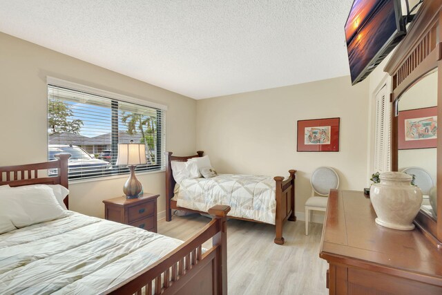 212 Club Dr, Palm Beach Gardens, FL 33418 - bedroom with light wood-style floors, a textured ceiling, a closet, and baseboards