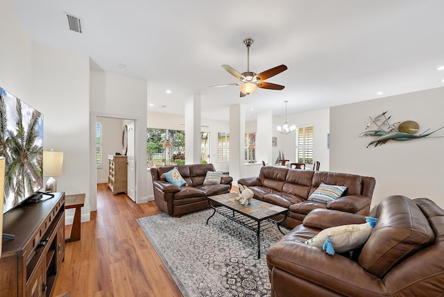 living room with light hardwood / wood-style flooring and ceiling fan with notable chandelier