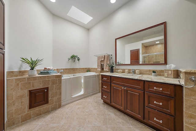 bathroom featuring vanity, lofted ceiling with skylight, tile patterned floors, and separate shower and tub