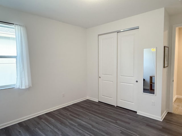 unfurnished bedroom featuring dark hardwood / wood-style flooring and a closet