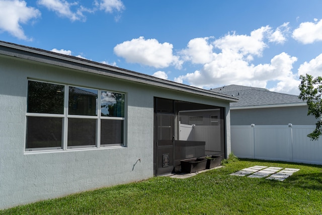 rear view of house with a lawn and a sunroom