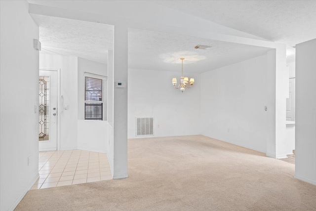 unfurnished room featuring a notable chandelier, a textured ceiling, and light colored carpet