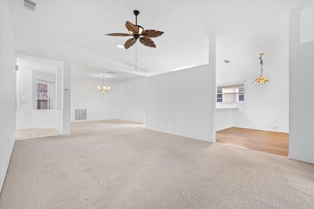 carpeted spare room with ceiling fan and vaulted ceiling