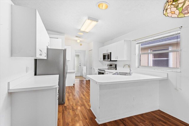 kitchen with washer / dryer, white cabinets, light hardwood / wood-style flooring, sink, and stainless steel appliances