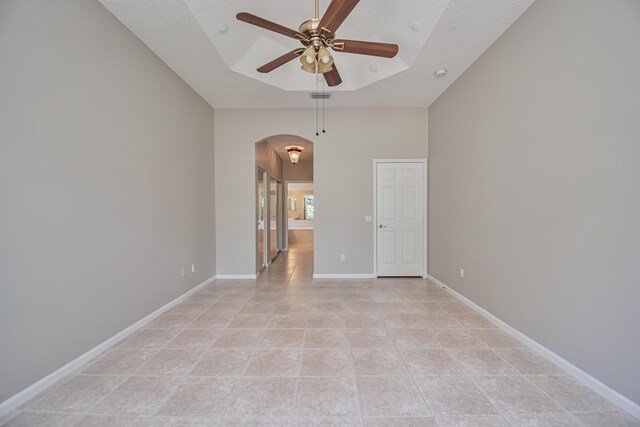 11481 Kanapali Ln, Boynton Beach, FL 33437 - empty room with arched walkways, a ceiling fan, light tile patterned flooring, a textured ceiling, and baseboards