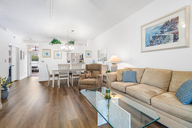 living room featuring dark wood-type flooring, a textured ceiling, and an inviting chandelier