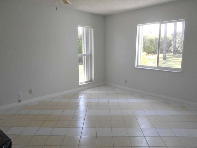 tiled spare room featuring a textured ceiling and ceiling fan