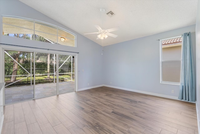 empty room featuring a textured ceiling, high vaulted ceiling, light hardwood / wood-style flooring, and ceiling fan