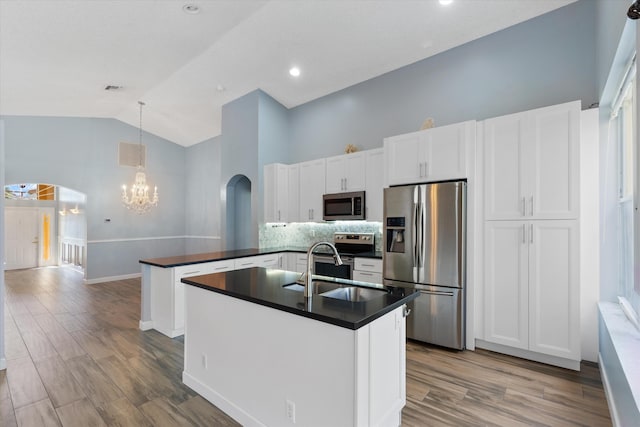 kitchen with a center island with sink, kitchen peninsula, hardwood / wood-style flooring, white cabinetry, and appliances with stainless steel finishes