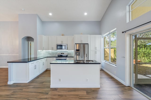 kitchen featuring dark wood-type flooring, appliances with stainless steel finishes, a high ceiling, and white cabinets