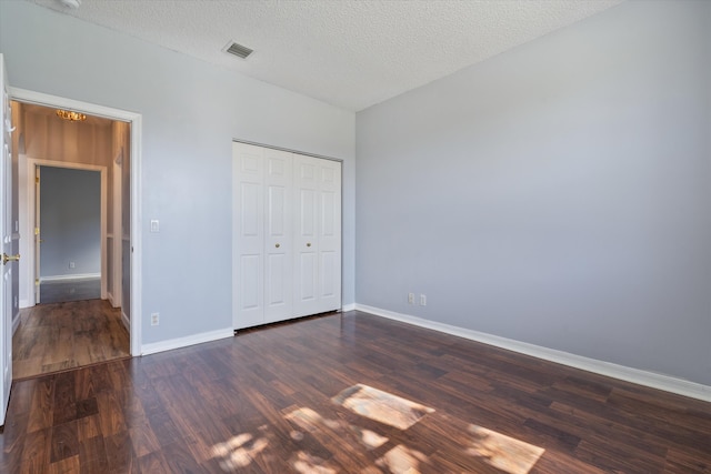 unfurnished bedroom featuring dark hardwood / wood-style flooring, a textured ceiling, and a closet