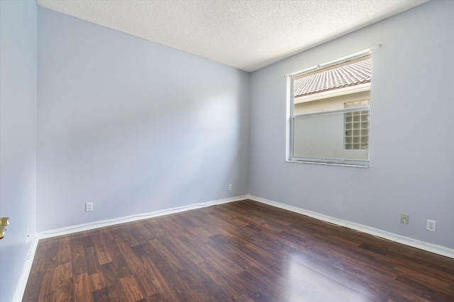 empty room featuring dark wood-type flooring and a textured ceiling