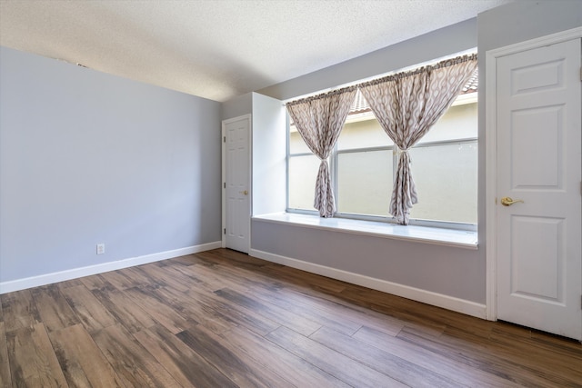 empty room with hardwood / wood-style flooring and a textured ceiling