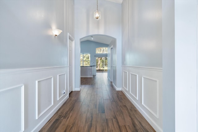 corridor with dark hardwood / wood-style flooring and vaulted ceiling