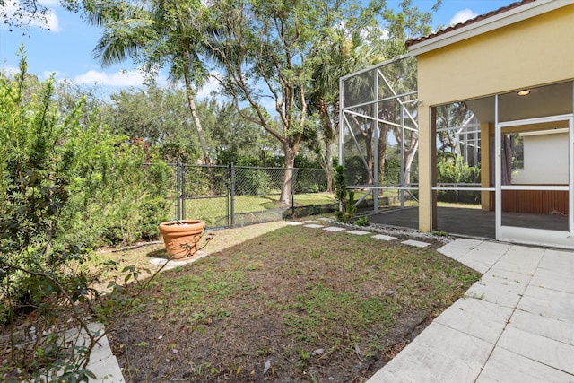 view of yard featuring glass enclosure and a patio