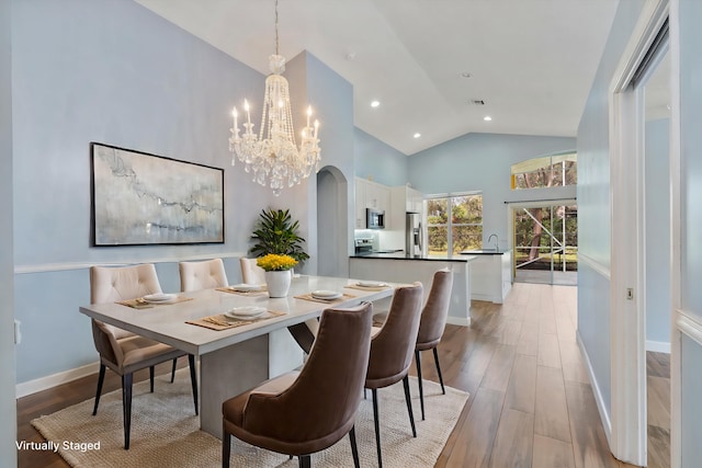 dining space featuring high vaulted ceiling, sink, and light hardwood / wood-style floors