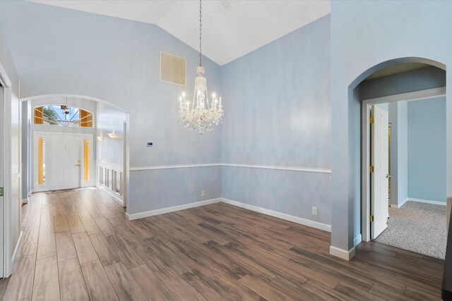 interior space featuring dark wood-type flooring, high vaulted ceiling, and a notable chandelier