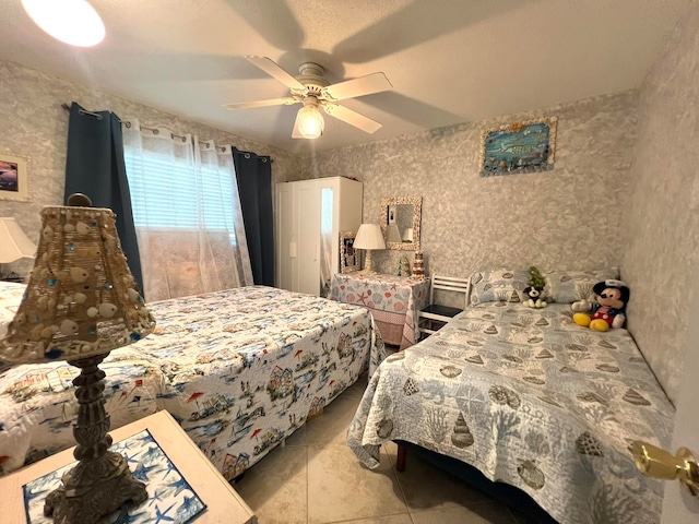 bedroom with ceiling fan, light tile patterned floors, and a textured ceiling