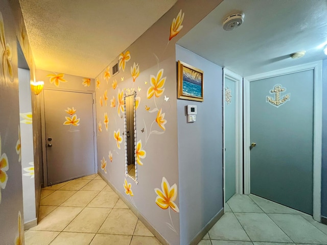 hall with a textured ceiling and light tile patterned flooring