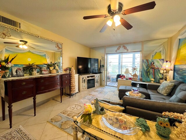 living room featuring ceiling fan, light tile patterned floors, and a textured ceiling