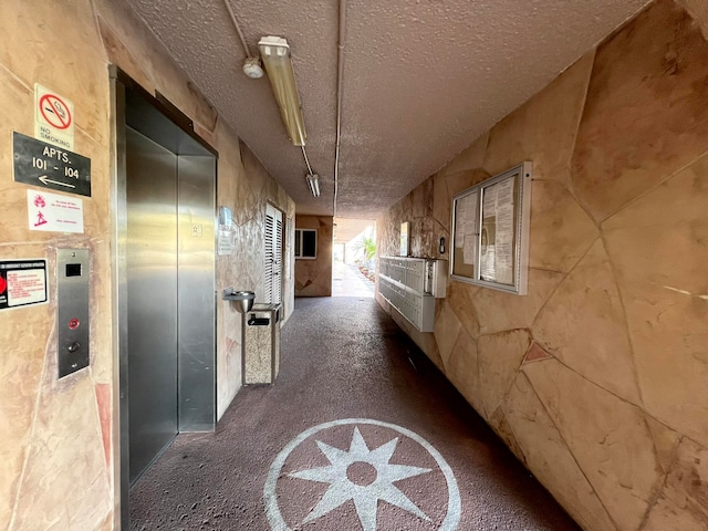 hallway featuring a textured ceiling and elevator