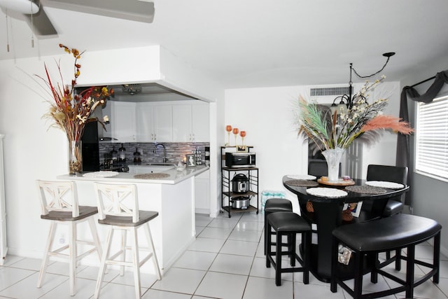 kitchen featuring kitchen peninsula, white cabinetry, sink, and decorative backsplash