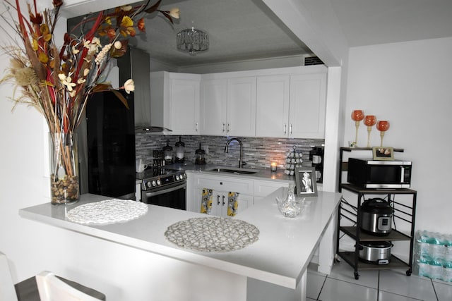 kitchen with white cabinets, appliances with stainless steel finishes, wall chimney range hood, and sink