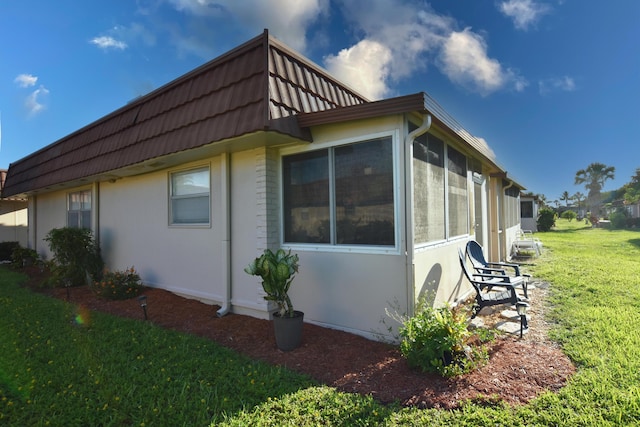 view of home's exterior featuring a sunroom and a yard