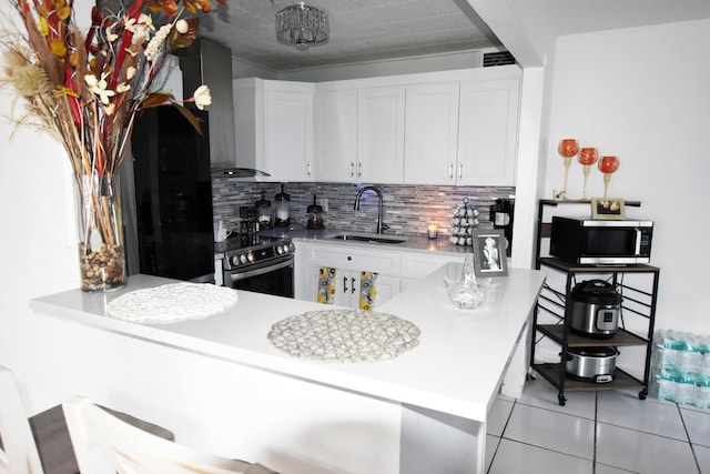 kitchen featuring sink, wall chimney exhaust hood, appliances with stainless steel finishes, tasteful backsplash, and white cabinetry