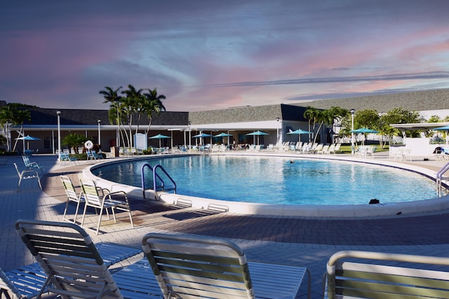 pool at dusk with a patio area