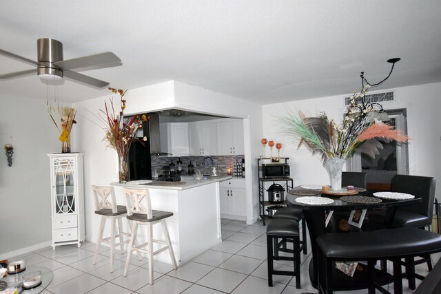 kitchen featuring white cabinets, a kitchen breakfast bar, tasteful backsplash, and light tile patterned floors