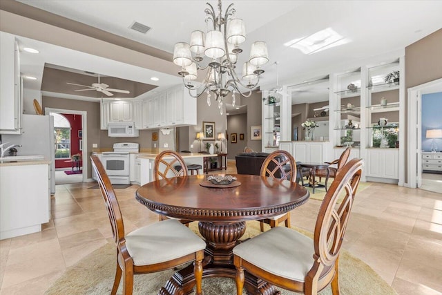 tiled dining area with ceiling fan with notable chandelier and a raised ceiling