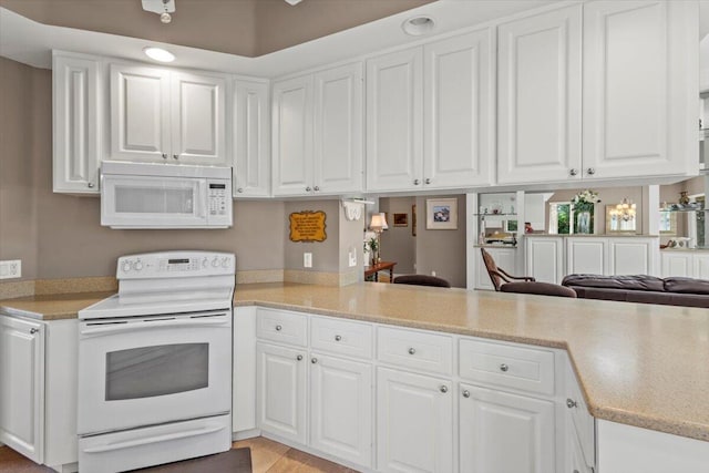 kitchen with white appliances, kitchen peninsula, and white cabinets