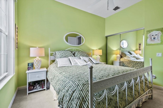 carpeted bedroom featuring multiple windows and a closet